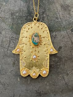 Hamsa Hand is very meaningful in many traditions. It's believed keep away from bad luck and negative things then turn them to Positive energy!! 21 ct gold plated brass. Turquoise and Pearl Length - Approx 83cm / top 6,5 x 5 cm Designed by our Turkish designer. Handcrafted with great care. Spiritual Turquoise Pendant Necklace For Festival, Artisan Handmade Necklace For Blessing Occasions, Artisan Handmade Jewelry For Blessing, Artisan Necklaces For Festivals, Bohemian Handmade Good Luck Necklace, Spiritual Turquoise Necklace For Festivals, Traditional Handmade Turquoise Pendant Necklace, Bohemian Round Pendant Necklace For Blessing, Amulet Style Jewelry With Large Pendant For Blessing