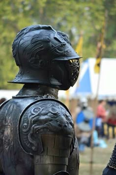 two people dressed in armor and helmets standing next to each other at an outdoor event