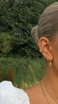 a woman in a white dress is smiling and wearing gold earrings on her ears