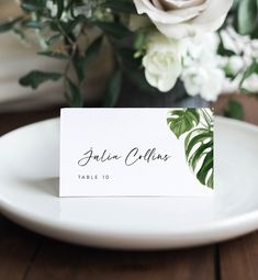 a place card sitting on top of a white plate next to a bouquet of flowers