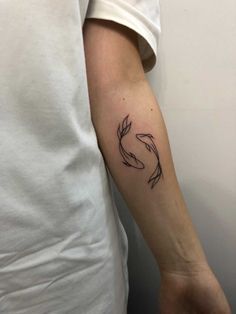 a person with a tattoo on their arm that has two fish swimming in the water