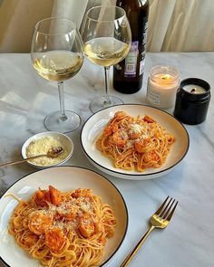 two plates of pasta and wine on a table