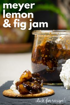 a glass jar filled with lemon and fig jam sitting on top of a table next to crackers