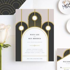 an art deco wedding suite is displayed on a table with white roses and gold accents