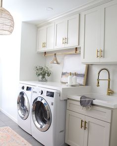 a washer and dryer in a room with white cabinets, counter tops and drawers