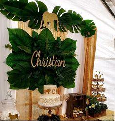 a table topped with a cake and lots of greenery next to a wall that says christian