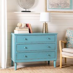 a blue dresser with books on top and a lamp next to it in a room