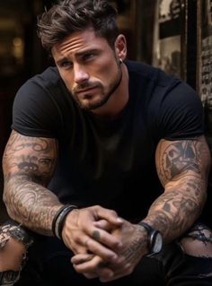 a man with tattoos on his arms sitting down and looking off to the side,