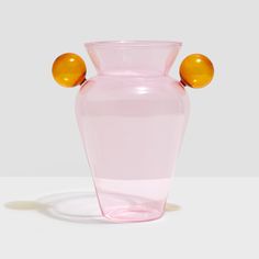 a pink glass vase with two yellow balls on the top and one orange ball at the bottom