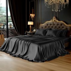 a bed with black sheets and a chandelier