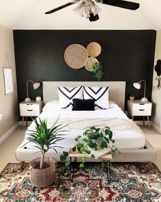 a white bed with black and white decor on the wall next to potted plants