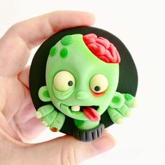 a hand holding a small green toy with a brain on it's head and eyes