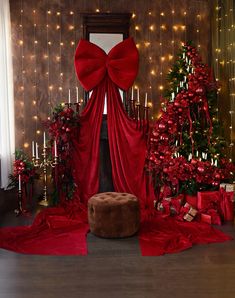 a room decorated for christmas with red decorations and lights on the wall, presents in front of a fireplace