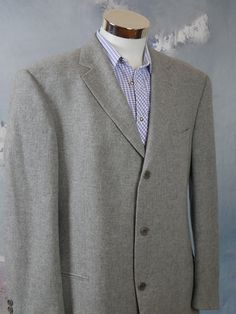 This retro menswear light gray wool Hugo Boss blazer has a notch collar and padded shoulders, and closes in the front with three gray buttons. Four buttons decorate each sleeve edge. The handsome European vintage jacket has two jetted hip pockets and one slanted jetted pocket on the left chest. The blazer is fully lined in a silver satin polyamid-nylon fabric, and has four inner pockets. Chest = 46 inches (116.84cm) (the extra 2 inches here allow for what you wear under) Shoulder Width = 21 inch Winter Gray Single-breasted Suit, Classic Gray Sport Coat With Pockets, Gray Wool Single Breasted Sport Coat, Gray Wool Single-breasted Sport Coat, Gray Semi-formal Sport Coat With Pockets, Classic Gray Single Breasted Sport Coat, Classic Gray Long Sleeve Sport Coat, Classic Gray Single-breasted Sport Coat, Mens Sport Coat