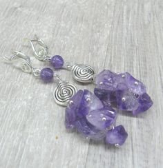 Extra long artisan earrimgs with natural amethyst crystal chips in a thick cluster. In one pair of earrings I combines several shapes: gemstone chips, disc with a spiralpattern and silver swirls looking a little like music symbol - G clef. Length: 78 mm or 2.75 inches from ear holeto the bottom. Amethyst cluster - 25 mm long and 16 mm wide. Amethhyst round bead: 6 mm Round silver plated disc bead with spiral pattern: 11 mm. G clef shaped earring top: 17 mm. I have a matching necklace available h Romantic Gifts For Girlfriend, Music Symbol, Valentine Jewelry, Crystal Chips, Earrings Purple, Spiral Pattern, Amethyst Cluster, Agate Ring, Valentines Jewelry