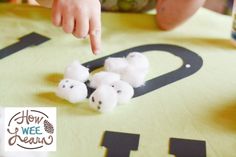 a child is playing with cotton balls on a tablecloth that has the letter d spelled out