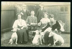 an old black and white photo of people with dogs