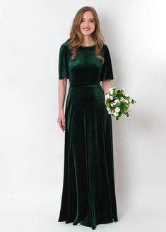 a woman in a long green dress holding a bouquet