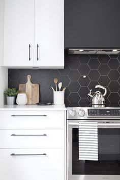 a stove top oven sitting inside of a kitchen next to white cupboards and drawers