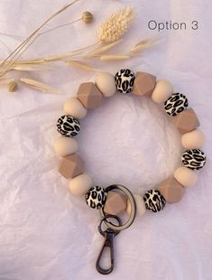 an animal print bracelet with a keychain on it and a wheat stalk in the background