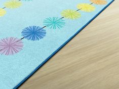 a blue rug with colorful umbrellas on the top and bottom, sitting on a wooden floor