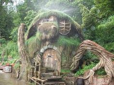 a hobbot house made out of trees in the forest with water running through it