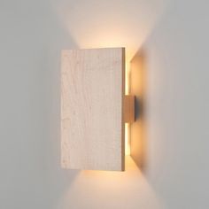 a wall mounted light that is on the side of a wall with a wooden block in front of it