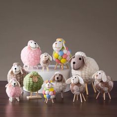 a group of sheep standing on top of a wooden table next to each other in front of a cake