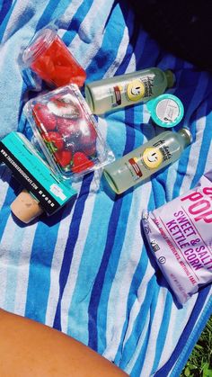 the contents of a picnic bag are laid out on a towel, including toothpaste, and other items