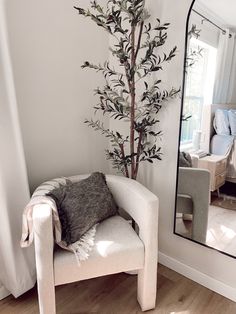 a white chair sitting in front of a mirror on top of a hard wood floor