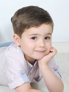 a little boy laying on the floor with his hand under his chin and looking at the camera