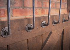 four metal handles on the side of a wooden door with bars attached to it and brick wall behind them