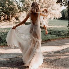 a woman in a dress walking down a dirt road