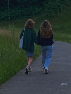 two women walking down a path holding hands