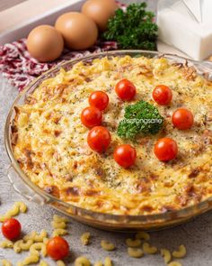 a casserole dish with tomatoes and cheese on the top, surrounded by eggs