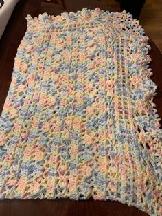 a crocheted blanket laying on top of a wooden table