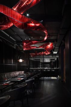 a dimly lit restaurant with red lights hanging from the ceiling and black leather booths on either side