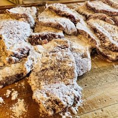 a wooden table topped with pastries covered in powdered sugar