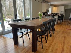 a dining room table and chairs in front of large windows