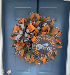 an orange and black wreath on a blue door with the words life's a journey not the road