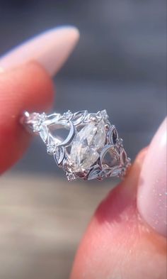 a close up of a person's hand holding an engagement ring