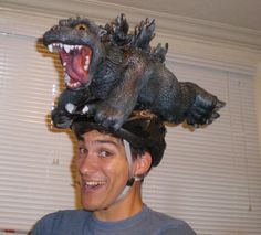 a young man is wearing a fake dinosaur head