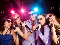 a group of people standing around each other holding microphones and singing into the microphone