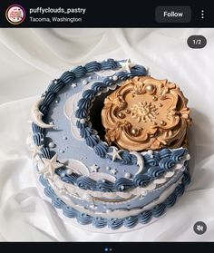 there is a blue and white cake with gold decorations on it's top, sitting on the table