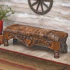 a wooden bench sitting on top of a rug next to a red vase and potted plant