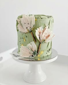 a green cake with flowers on it sitting on top of a white table next to an instagram post