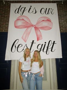 two women standing in front of a sign that says dog is our best gift