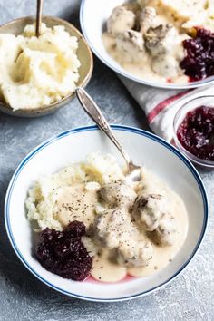 two bowls filled with mashed potatoes covered in gravy and cranberry sauce