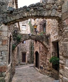 an alley way with stone buildings and plants growing on the walls