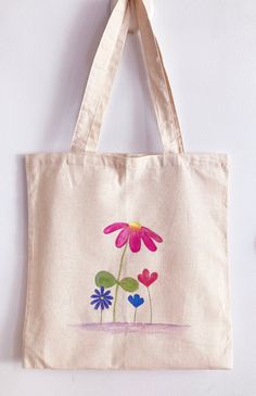 a canvas bag hanging on the wall with flowers painted on it's front and back